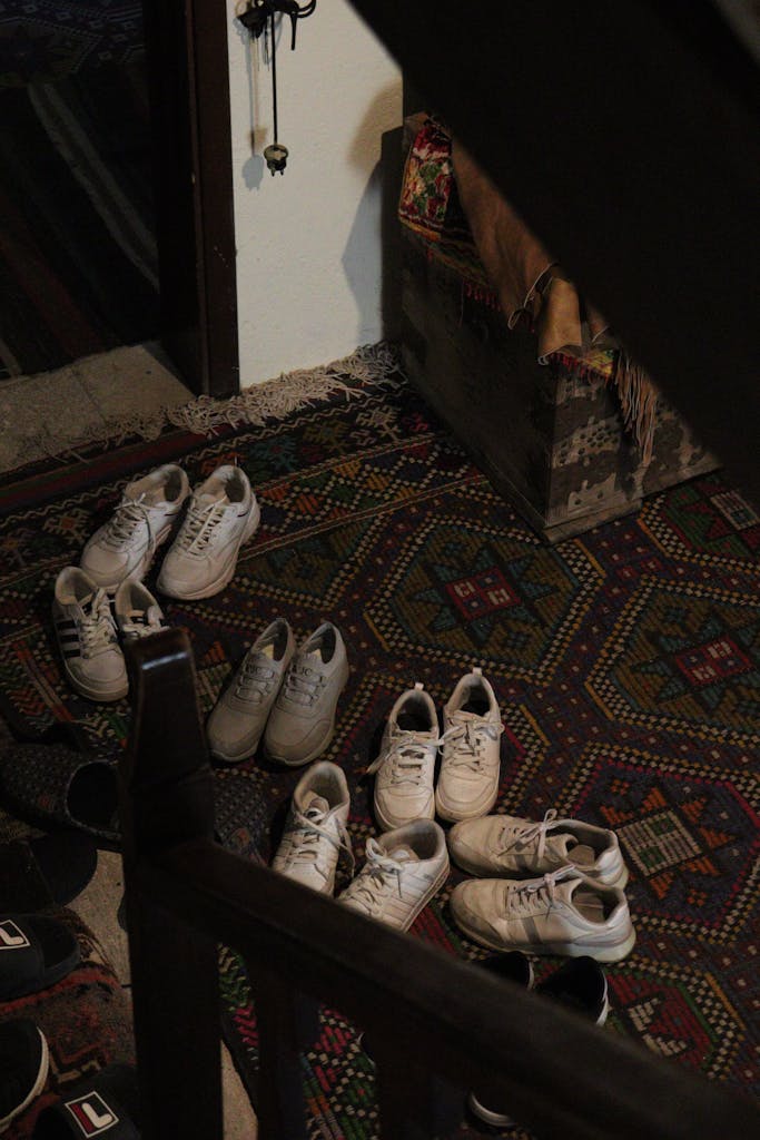 An inviting indoor space featuring multiple shoes on a vibrant geometric rug, capturing a welcoming home atmosphere.