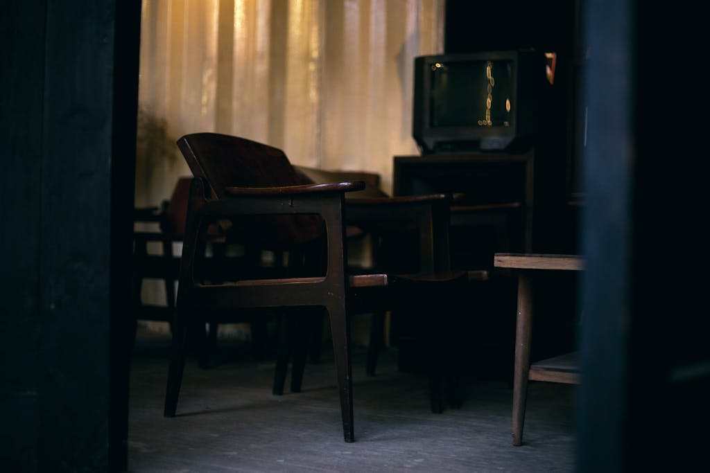 Dark and cozy interior with vintage wooden chairs and an old television in a room.