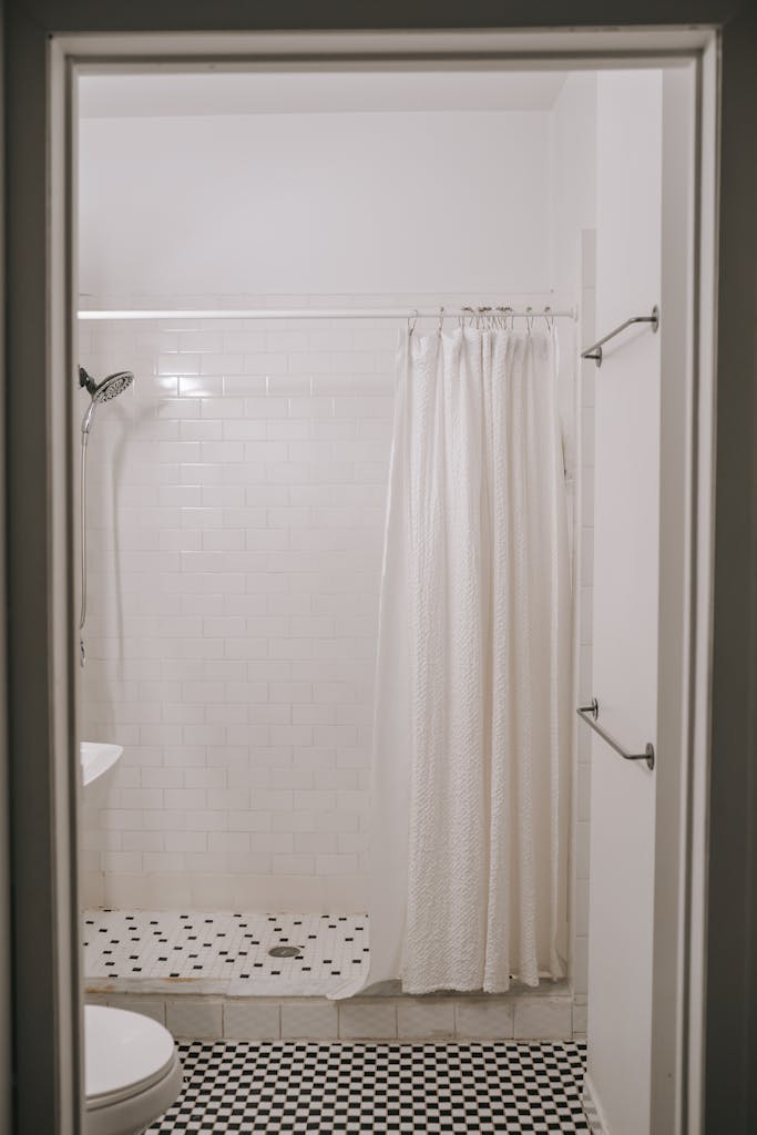 Elegant minimalist bathroom with a white shower curtain and tiled floor.